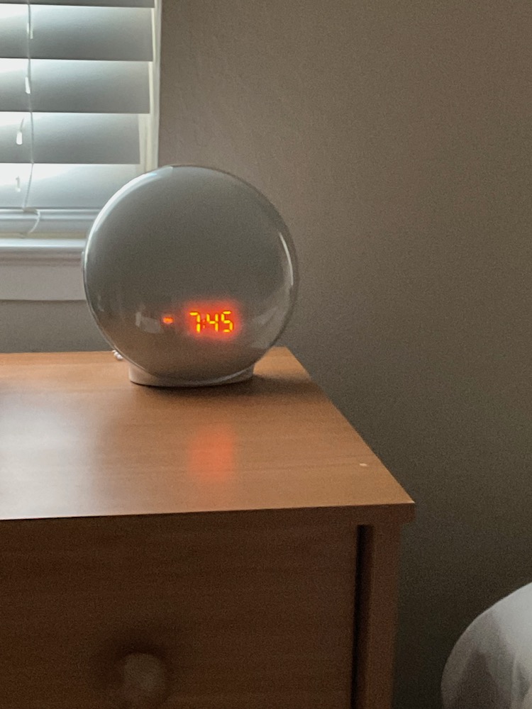 Image of a round alarm clock with glowing orange numbers in a cloudy orange haze